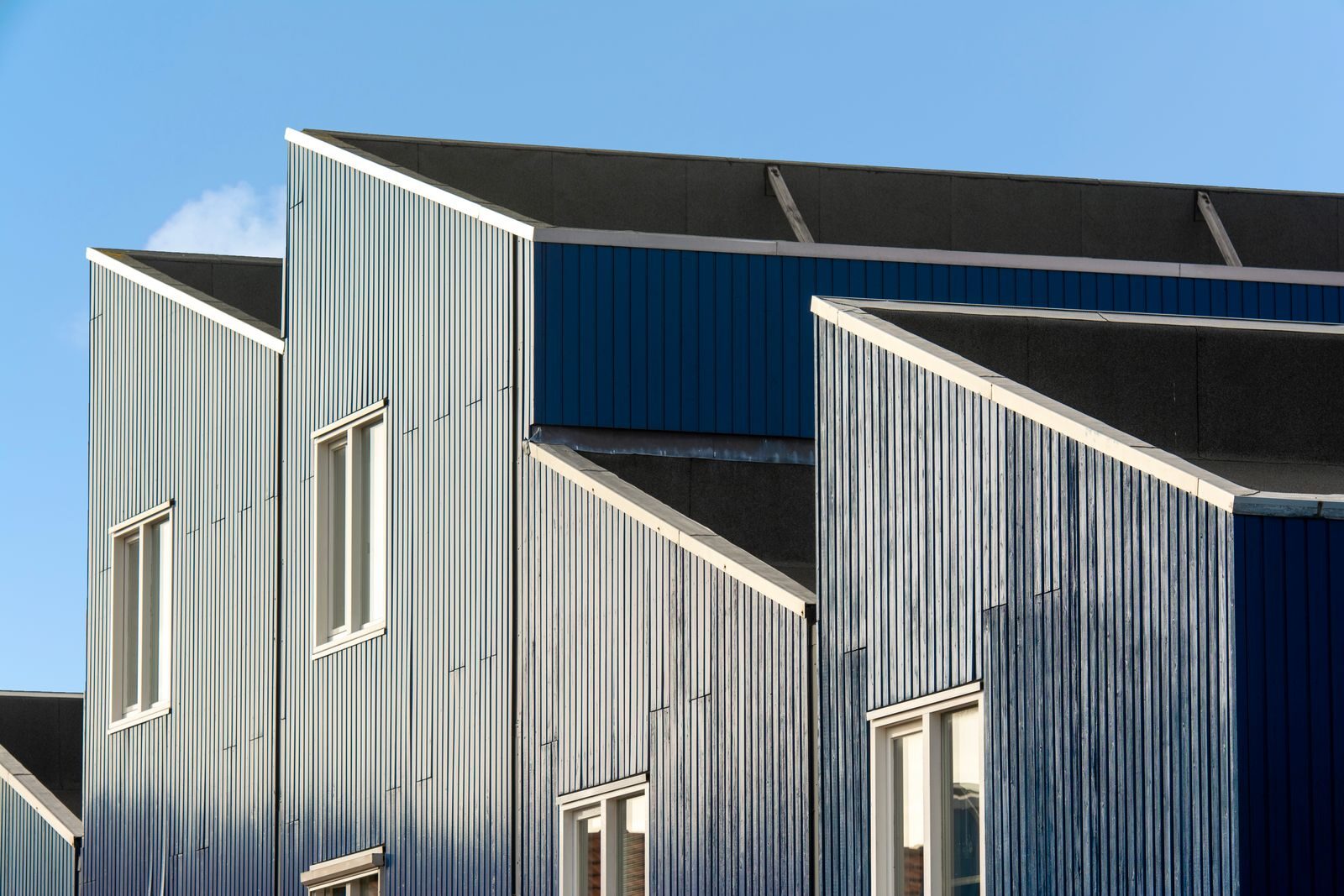 Contemporary geometric building facade with large windows under clear blue sky.